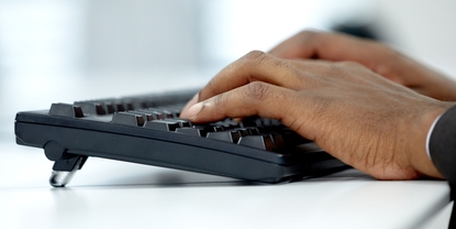 Hands typing on a computer keyboard.
