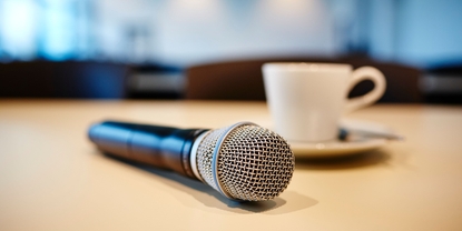 Ambiance de conférence de presse : microphone et tasse de café sur une table.