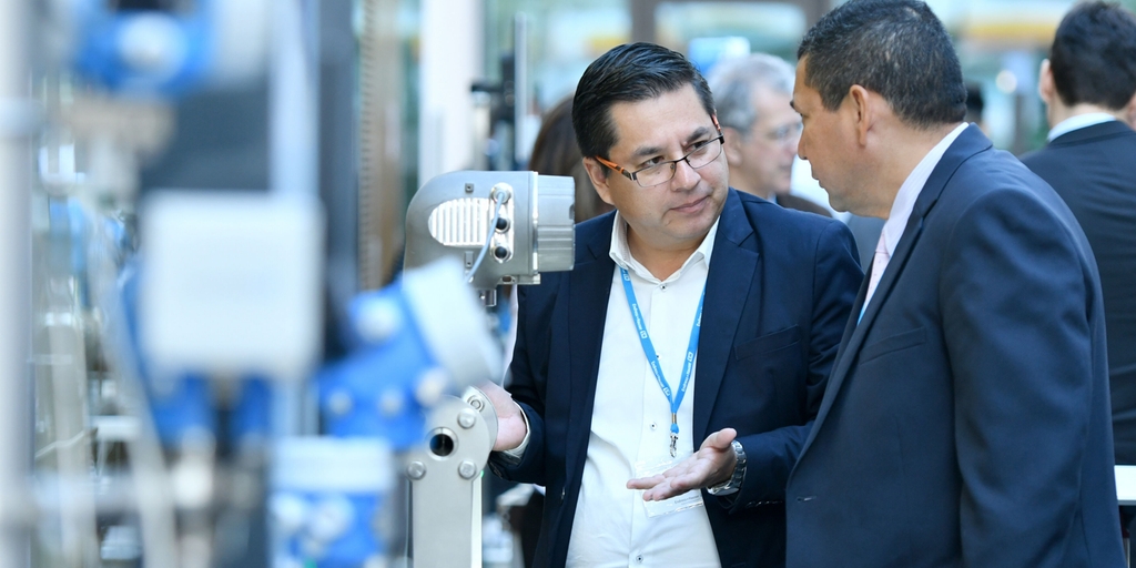 People discussing at a Endress+Hauser event in front of a exhibit.